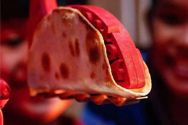 Toaster Taco Shell Maker in use, showcasing a taco being toasted, with colorful taco mold and smiling children in the background, perfect for creating crispy taco shells at home.