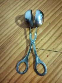 Metal scissors with rounded handles lying on a surface.