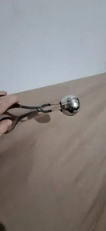 Metal tongs holding a shiny silver ball.